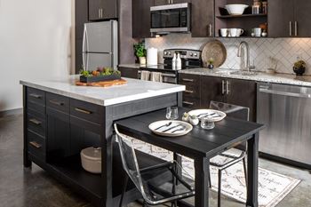 A modern kitchen with a black table and chairs.